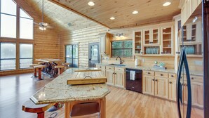 Eine geräumige Küche mit Holzschränken, einer Arbeitsplatte aus Granit und einer großen Kochinsel mit Hockern.