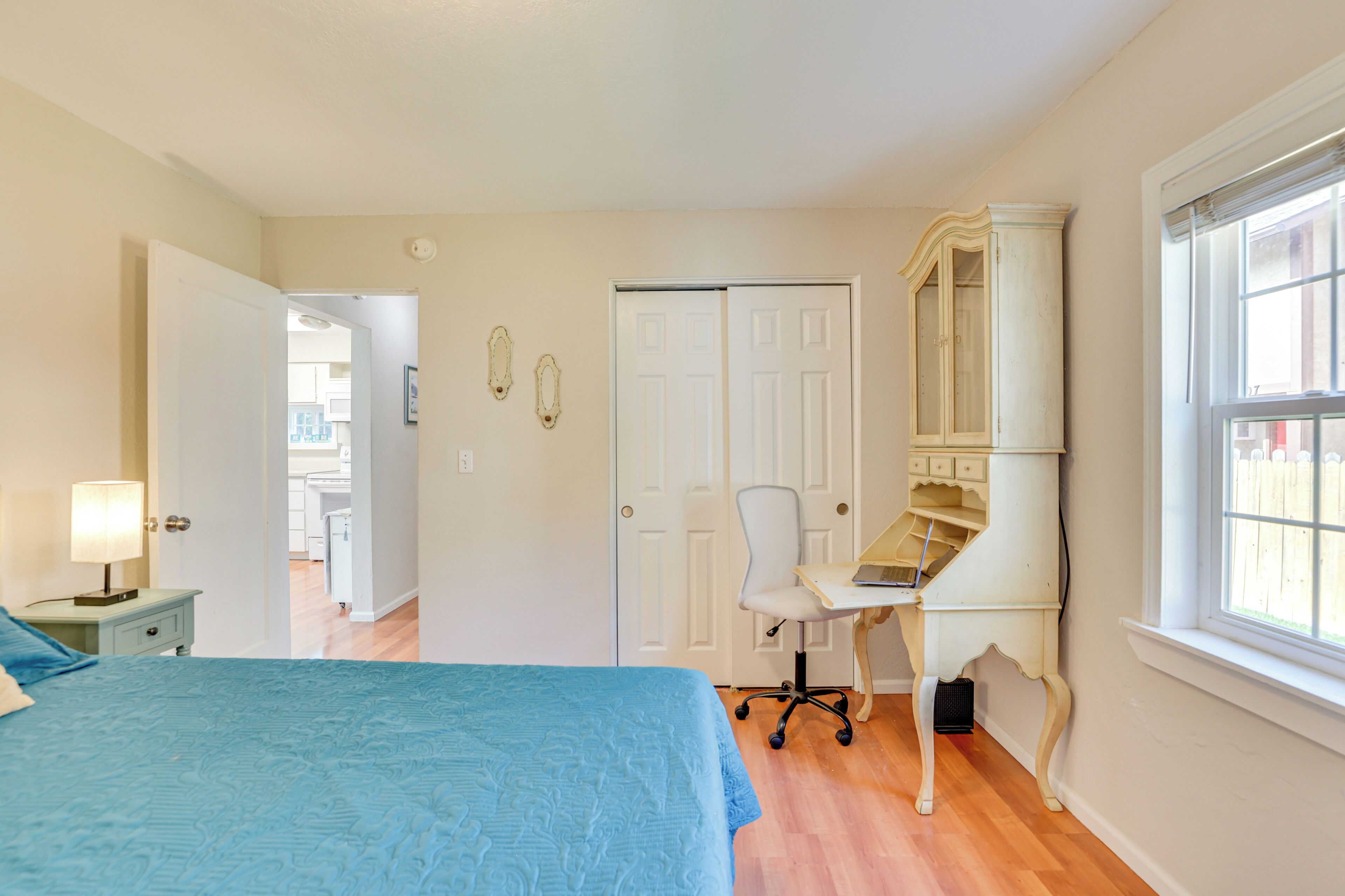 Une chambre à coucher comprenant un lit, un bureau, une chaise, une armoire et une fenêtre.