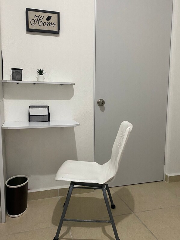 A white chair in front of a door, with a small shelf above holding a plant and a basket. - CASABONITA II pie de alberca AirAc (xochitepec)