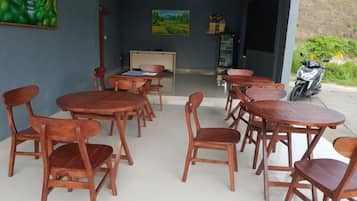 A dining area with wooden tables and chairs, a motorcycle outside, and a view of a garden.