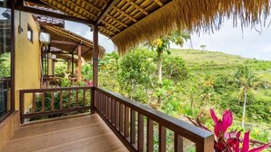 A wooden balcony with a thatched roof, overlooking a lush green landscape. - Nusa Penida Pini Sentana (Bali)
