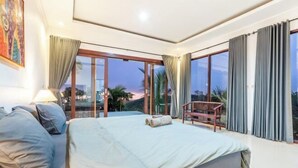 A bedroom with a large bed, a chair, and a view of the outdoors. - Nusa Penida Pini Sentana (Bali)