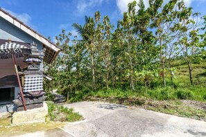 A traditional building with a thatched roof, a stone base, and a small shrine with offerings. - Nusa Penida Pini Sentana (Bali)