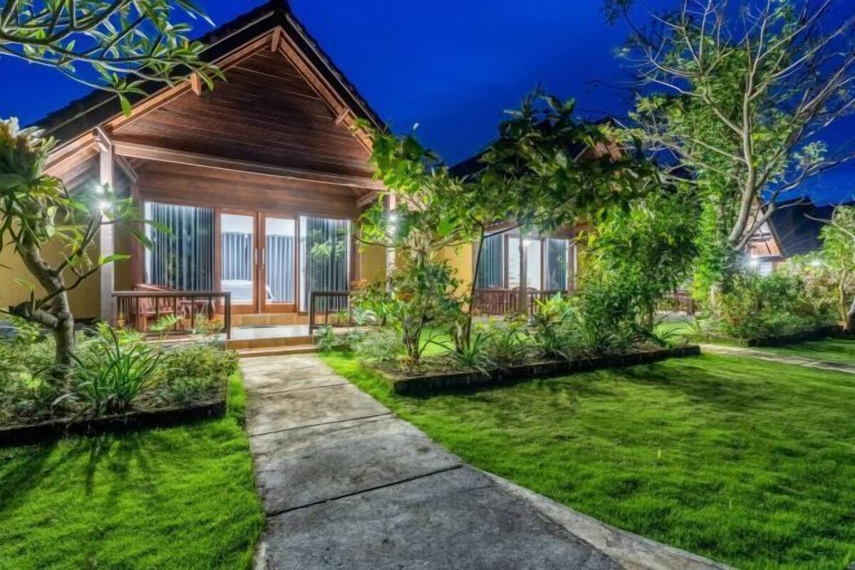 A well-maintained residential property with a wooden exterior, a paved driveway, and a lush green lawn.