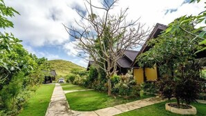 A residential property with a well-maintained lawn, a stone pathway leading to the entrance, and a variety of plants and trees. - Nusa Penida Pini Sentana (Bali)