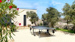 Un tavolo da ping pong all'aperto in un giardino con un muro in pietra e alberi.