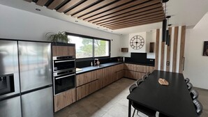 Una cucina moderna con elettrodomestici integrati, una zona pranzo con tavolo e sedie nere e un grande orologio a parete.