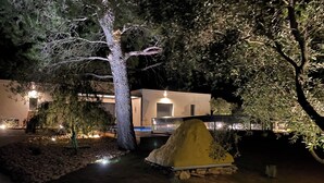 Una vista notturna di un edificio moderno con un ingresso ben illuminato e un vialetto in pietra che conduce alla porta.