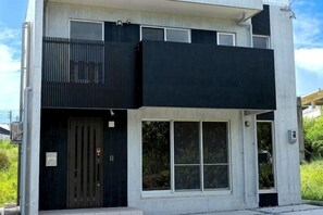 A modern two-story building with a balcony, large windows, and a door. - Naox I (Miyakojima)