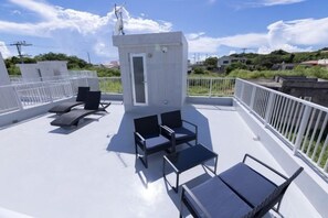 Una terraza en la azotea con una pequeña estructura blanca, dos sillones de relax y una mesa.