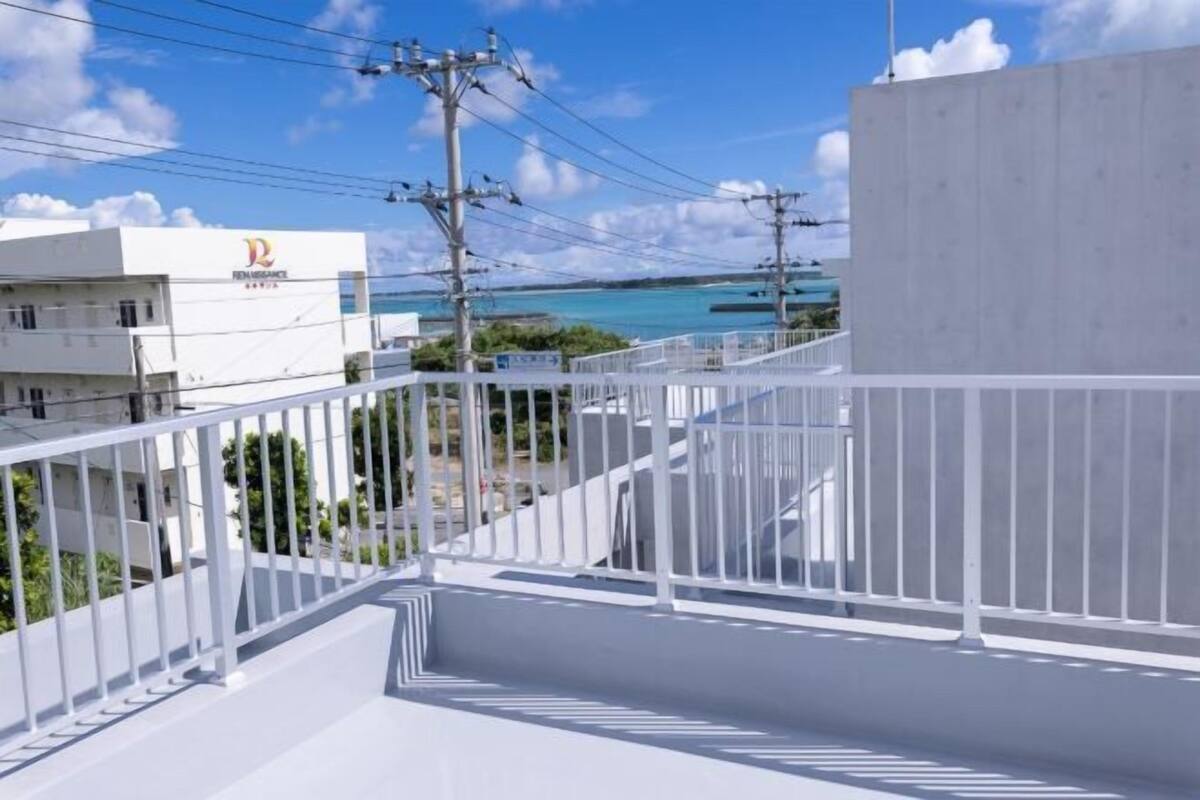 A balcony with a view of the sea and a building with a logo.