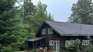 Una casa de madera rústica con un porche, una terraza y un pequeño espacio para sentarse al aire libre.