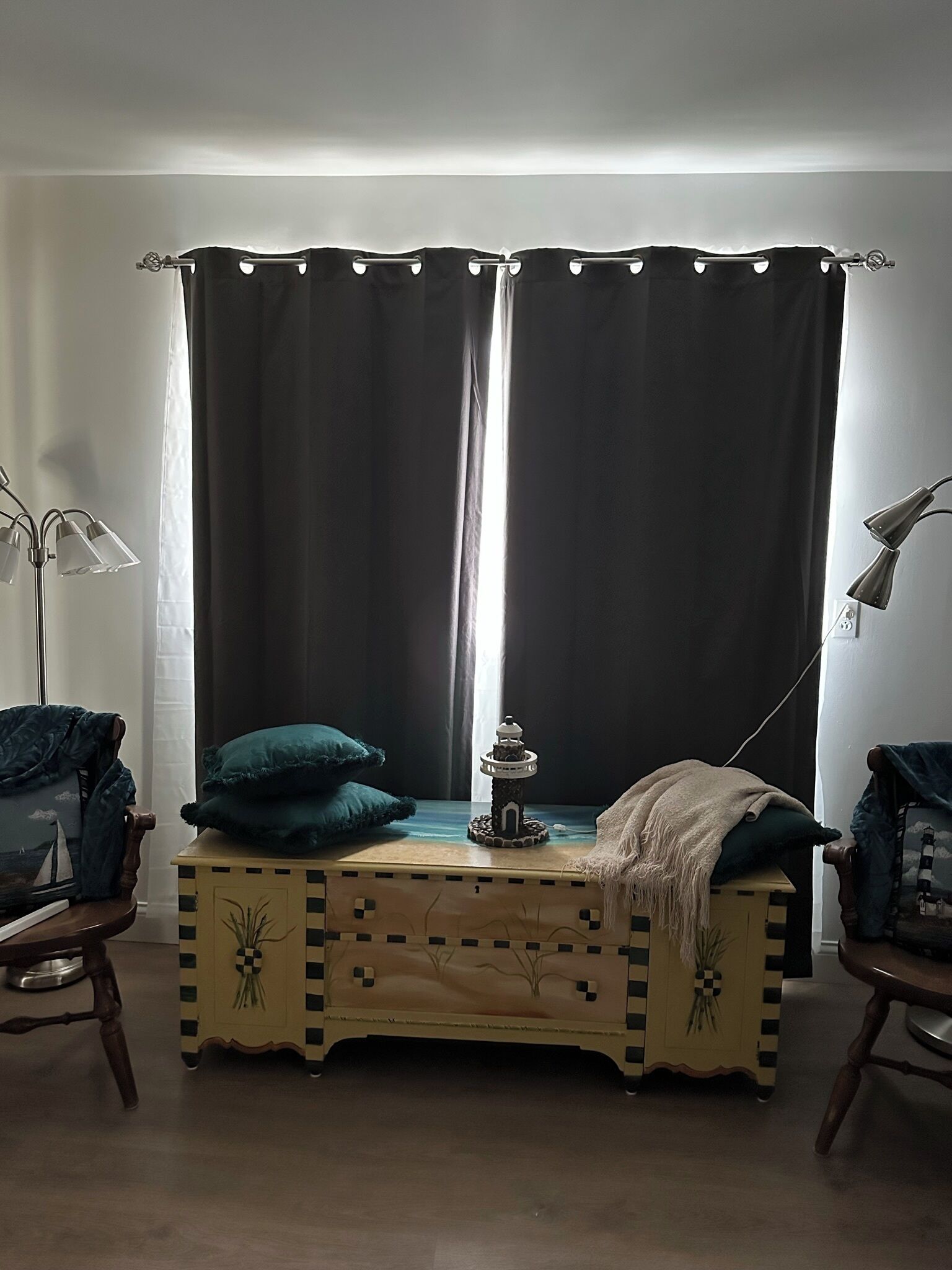 Ett rum med en säng, ett sängbord med en lampa, en liten prydnadsföremål och ett fönster med gardiner.