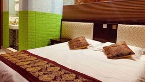 A hotel room with a bed, green and white patterned walls, a wooden headboard, and two decorative pillows. - Suihua Fashion Spring Express Hotel (Suihua)