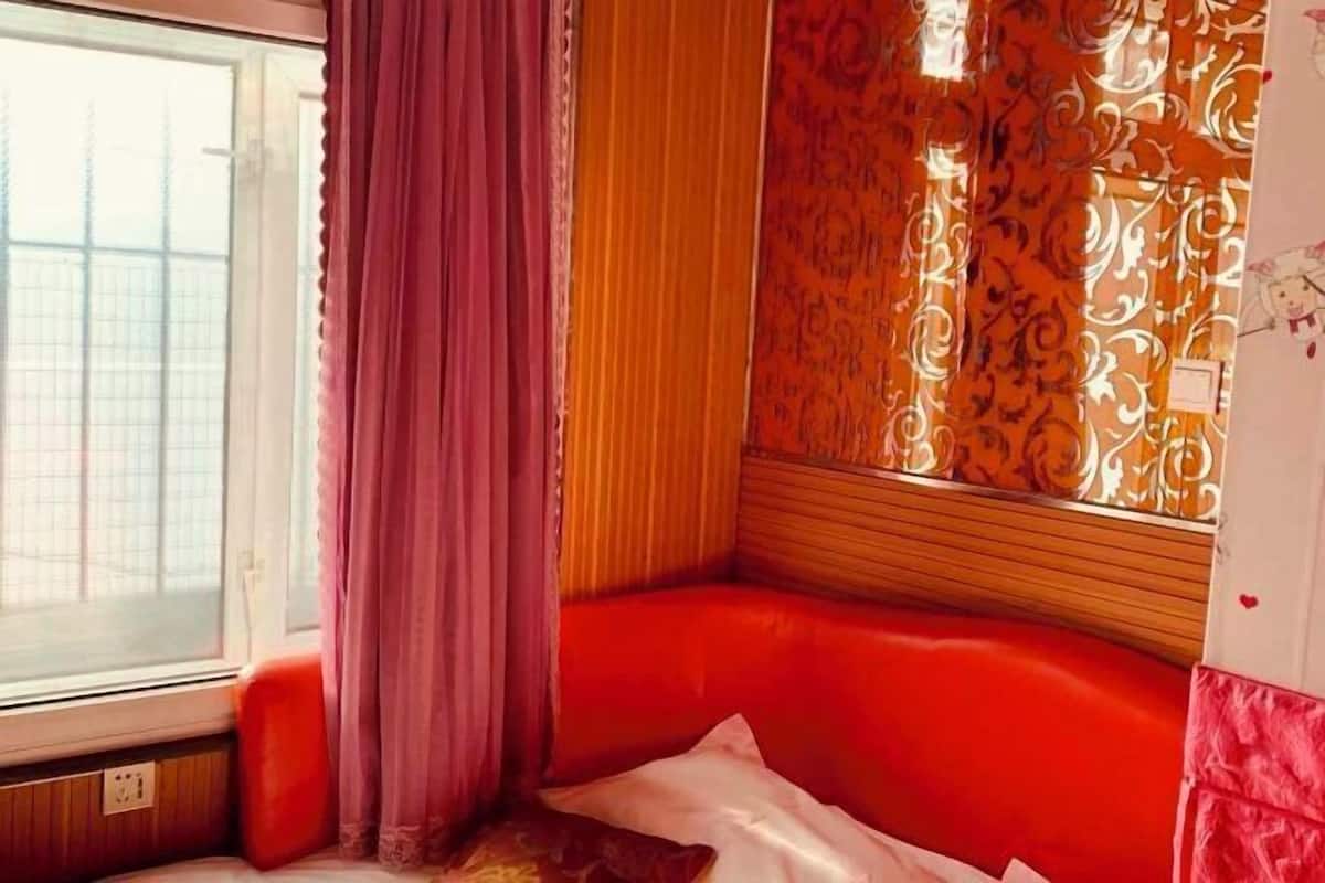 A room with a window, a red bench, and patterned wallpaper.