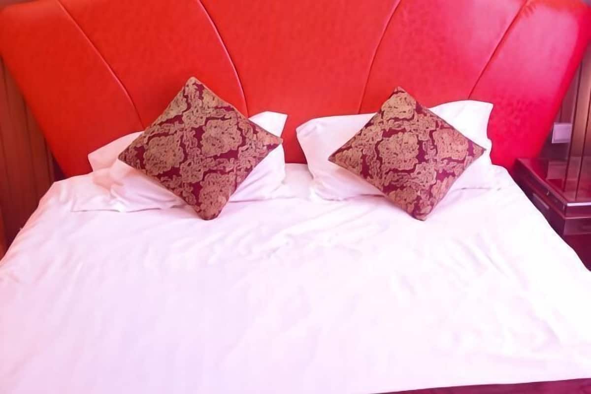 A bed with a red headboard and two decorative pillows.