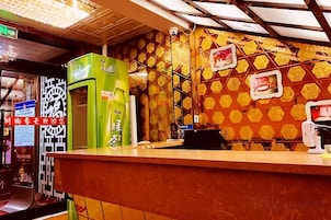 Un mostrador con una máquina expendedora verde, una pared con un diseño y un techo con tragaluces.