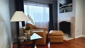 A living room with a sofa, ottoman, glass coffee table, lamp, and a fireplace. - Spacious 4-bedroom house in charming Des Plaines with AC, WiFi (Des Plaines)