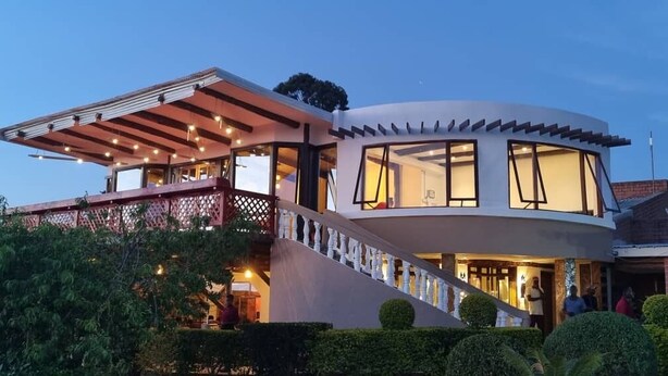 Una casa moderna con facciata curva, ampie finestre e una zona esterna coperta con illuminazione.
