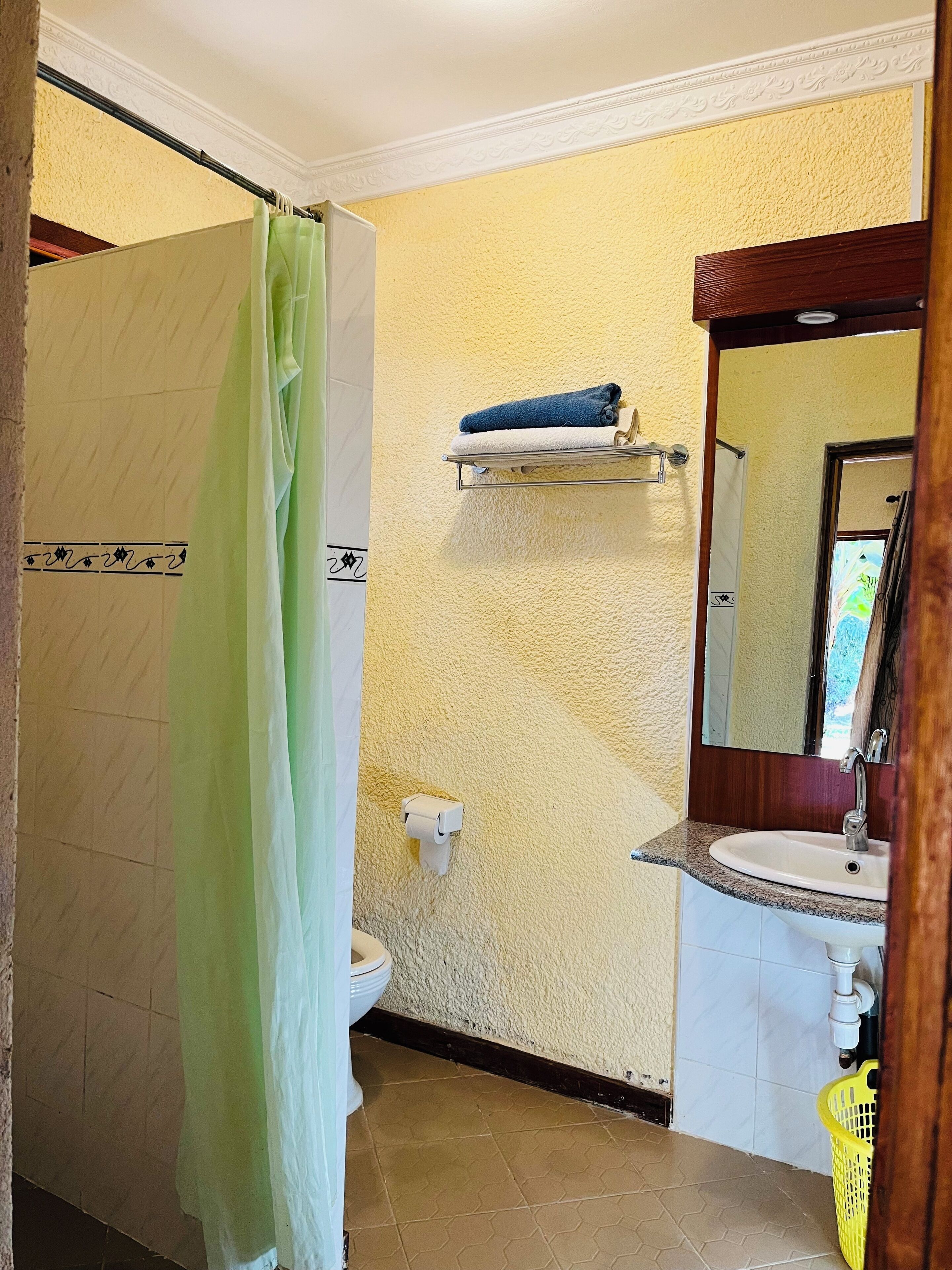 Un baño con inodoro, lavamanos y un perchero para toallas.