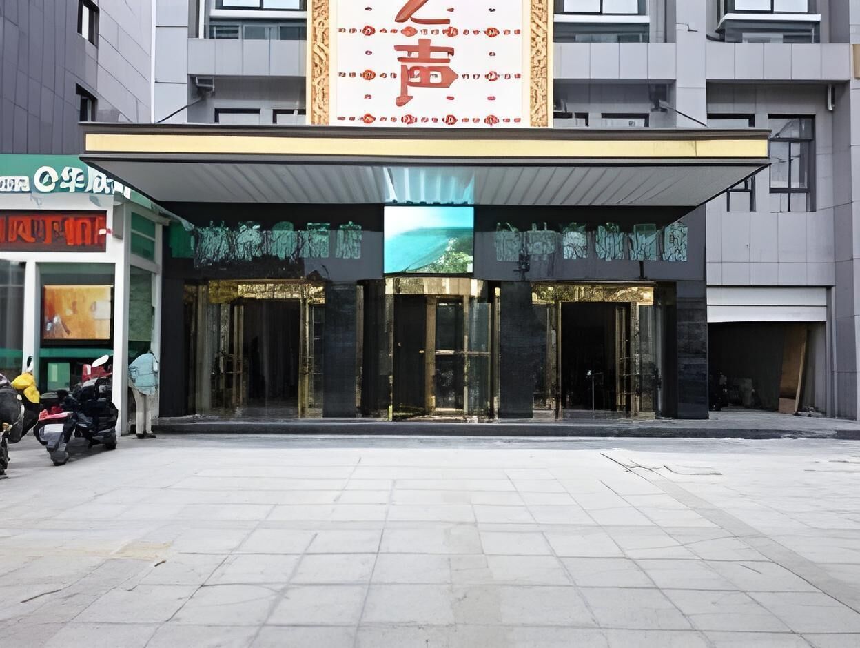 A modern building with a large entrance, glass doors, and a sign with Chinese characters.