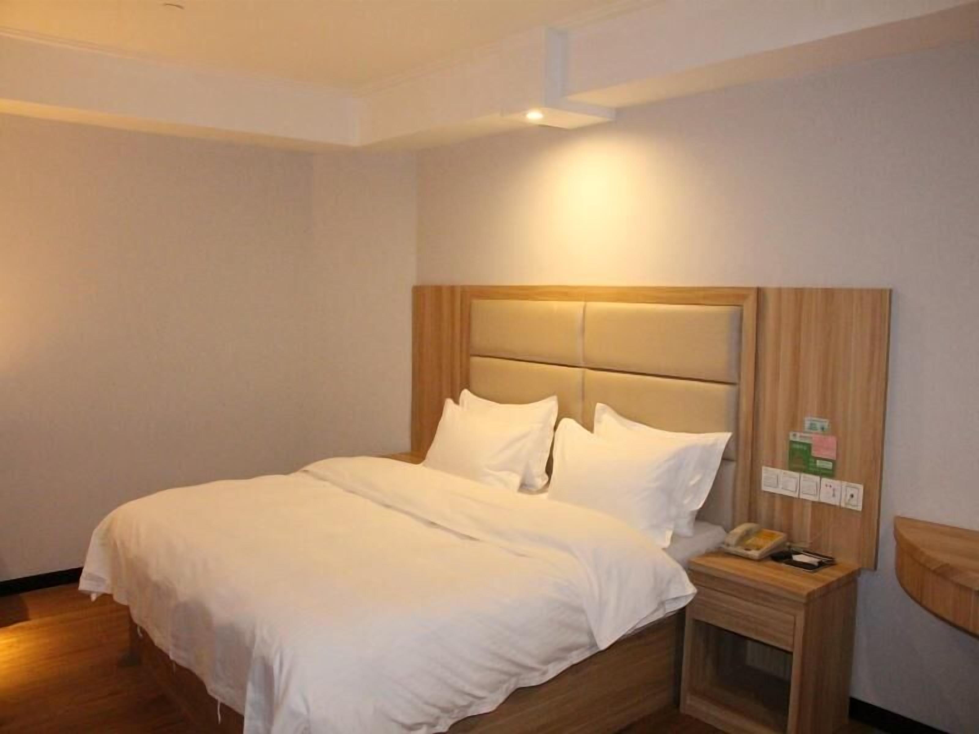 Habitación de hotel con cama, mesita de noche y teléfono en la pared.