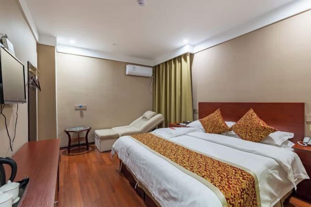 Una habitación de hotel con cama, escritorio, silla, equipo de aire acondicionado y una mesita.