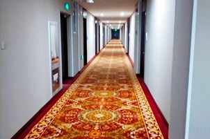 A long hallway with a patterned carpet and doors on both sides.