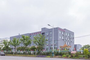 En modern byggnad med ett platt tak, flera fönster och en skylt med röd text.