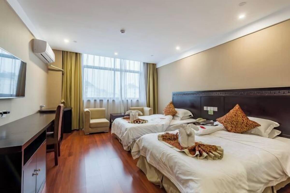 Una habitación de hotel con dos camas, un escritorio, una silla y un televisor.