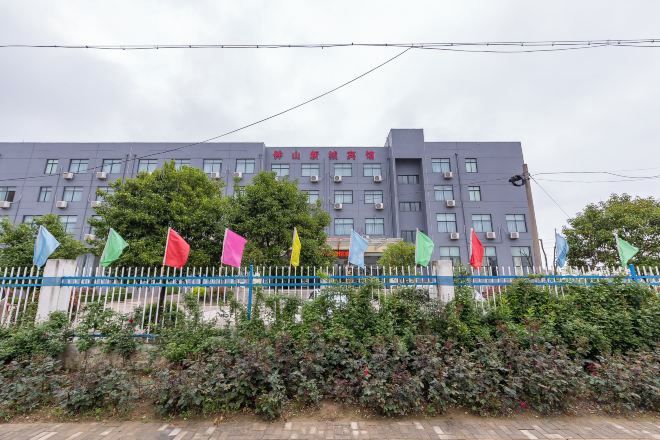Un edificio de varios pisos con una cerca azul y banderas de colores al frente.