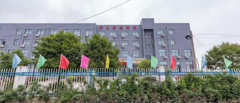 Un edificio de varios pisos con una cerca azul y banderas de colores al frente.