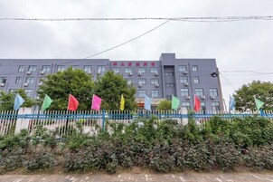 Un edificio de varios pisos con una cerca azul y banderas de colores al frente.