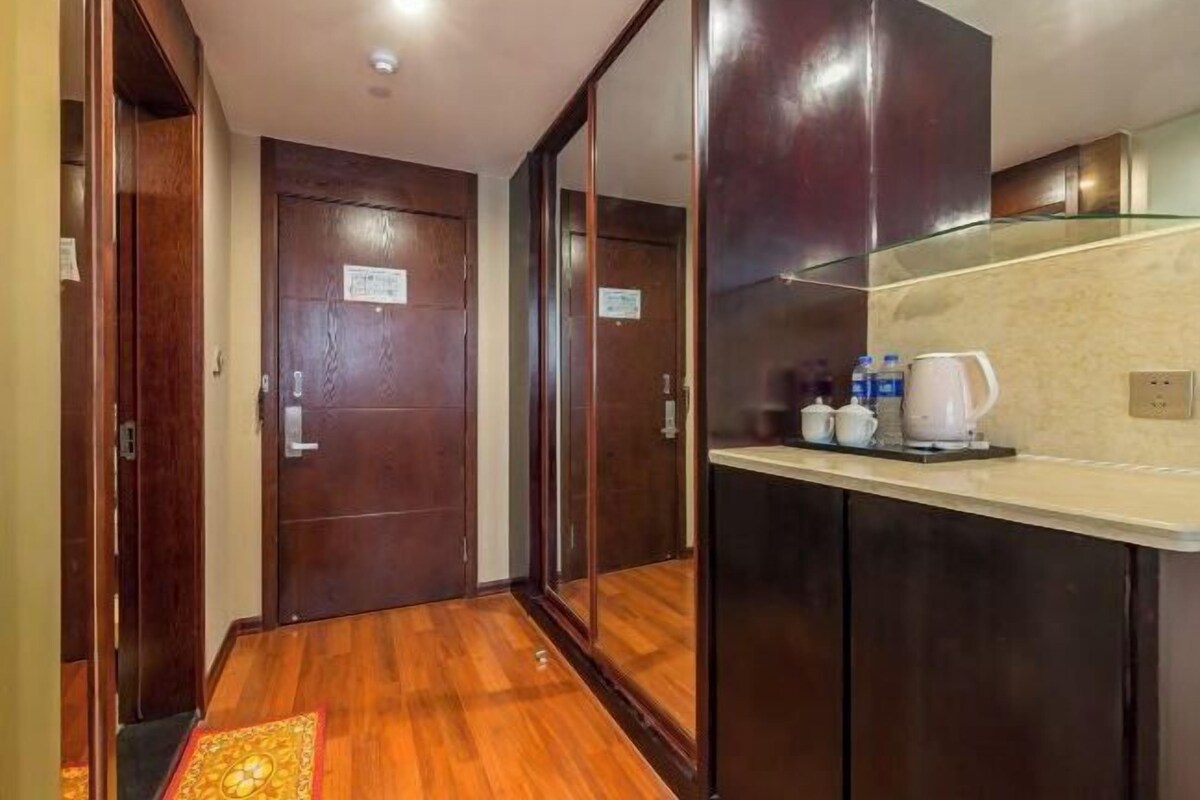 Un couloir d’hôtel avec des portes en bois, un coin cuisine doté d’un plan de travail et d’une machine à café.