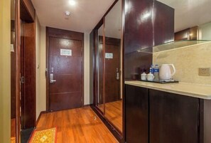 Un couloir d’hôtel avec des portes en bois, un coin cuisine doté d’un plan de travail et d’une machine à café.