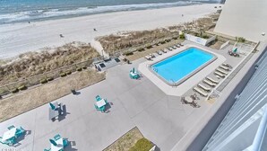 A rooftop pool with lounge chairs and a view of the beach.