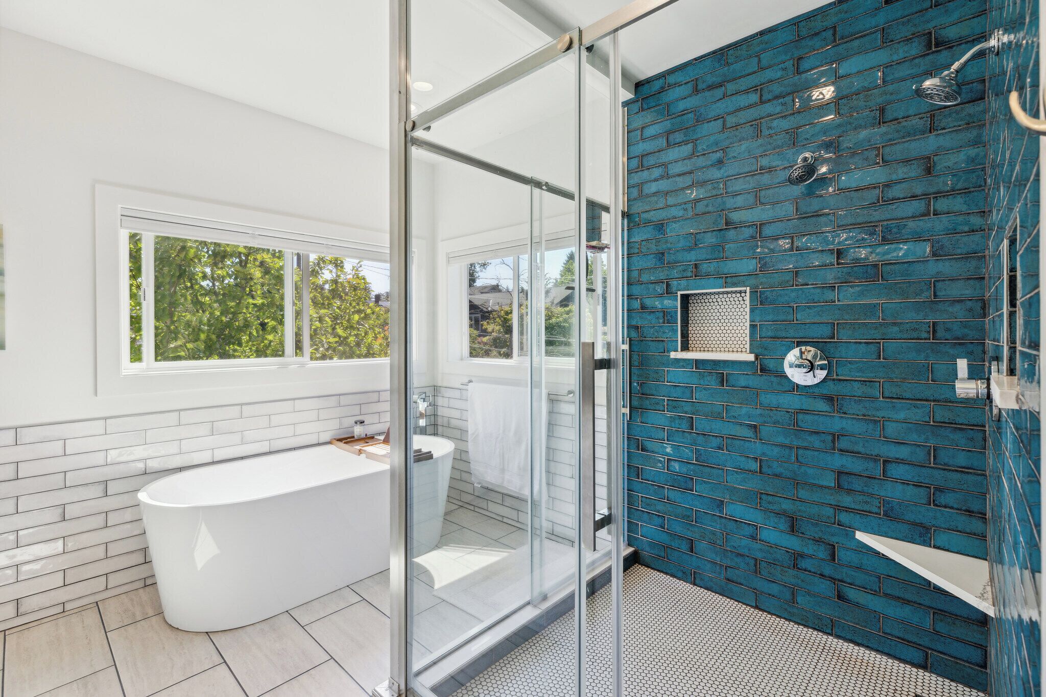 A modern bathroom with a freestanding bathtub, a glass shower enclosure, and a blue-tiled shower wall.