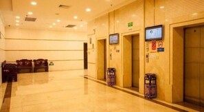 Eine Hotelhalle mit Empfangsschalter, Sitzgelegenheiten und Aufzügen.