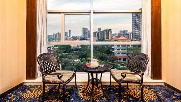 A room with a city view, two chairs, a small table, and patterned carpet. - Huiquan Hotel (Zhongshan)