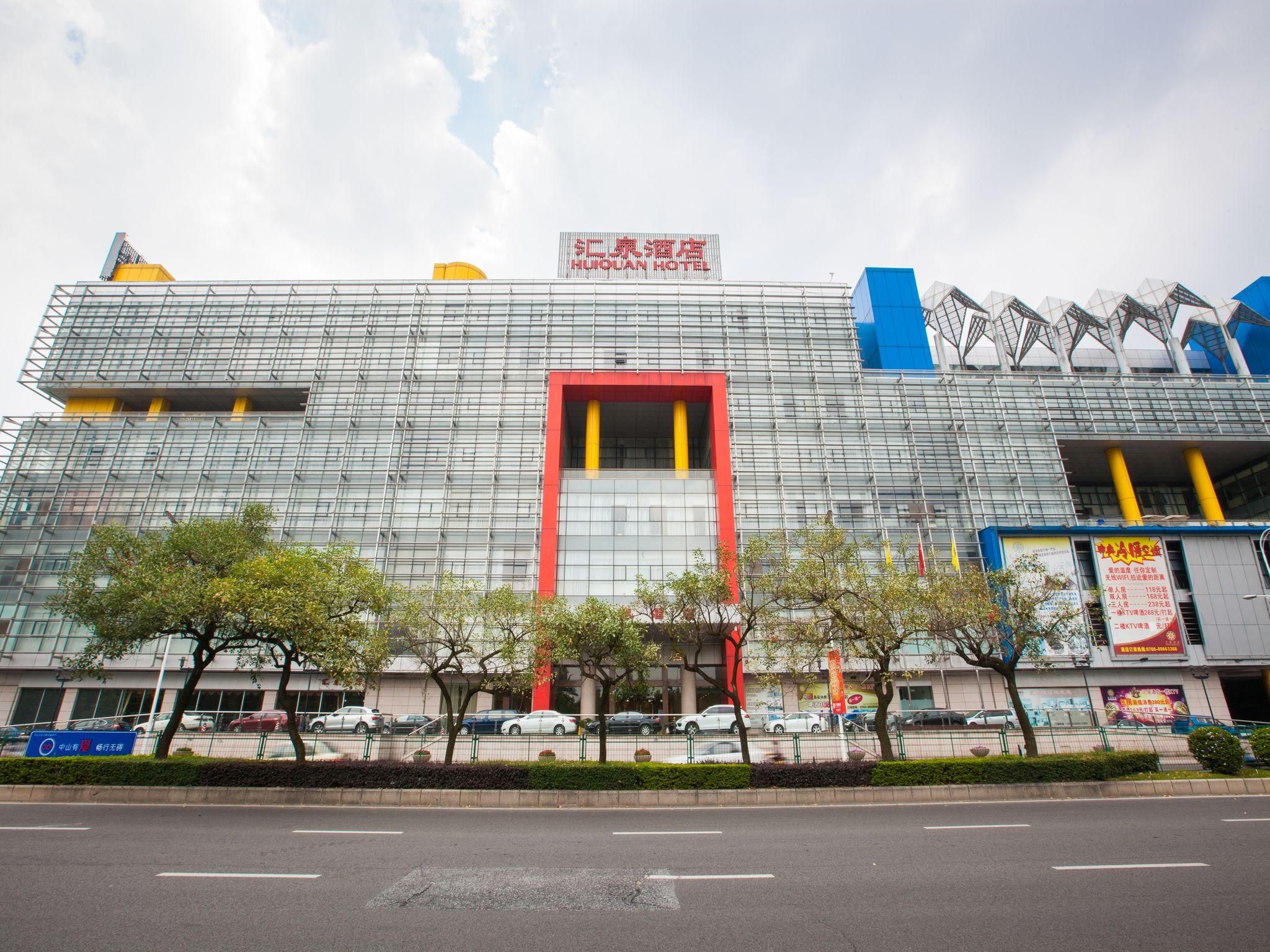 A modern hotel with a prominent red and yellow entrance, multiple floors, and a mix of glass and metal construction.
