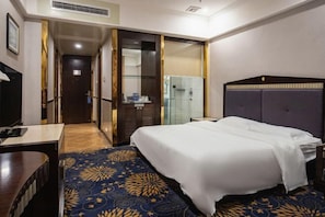 A hotel room with a bed, a desk, a mirror, and a bathroom visible through an open door. - Huiquan Hotel (Zhongshan)