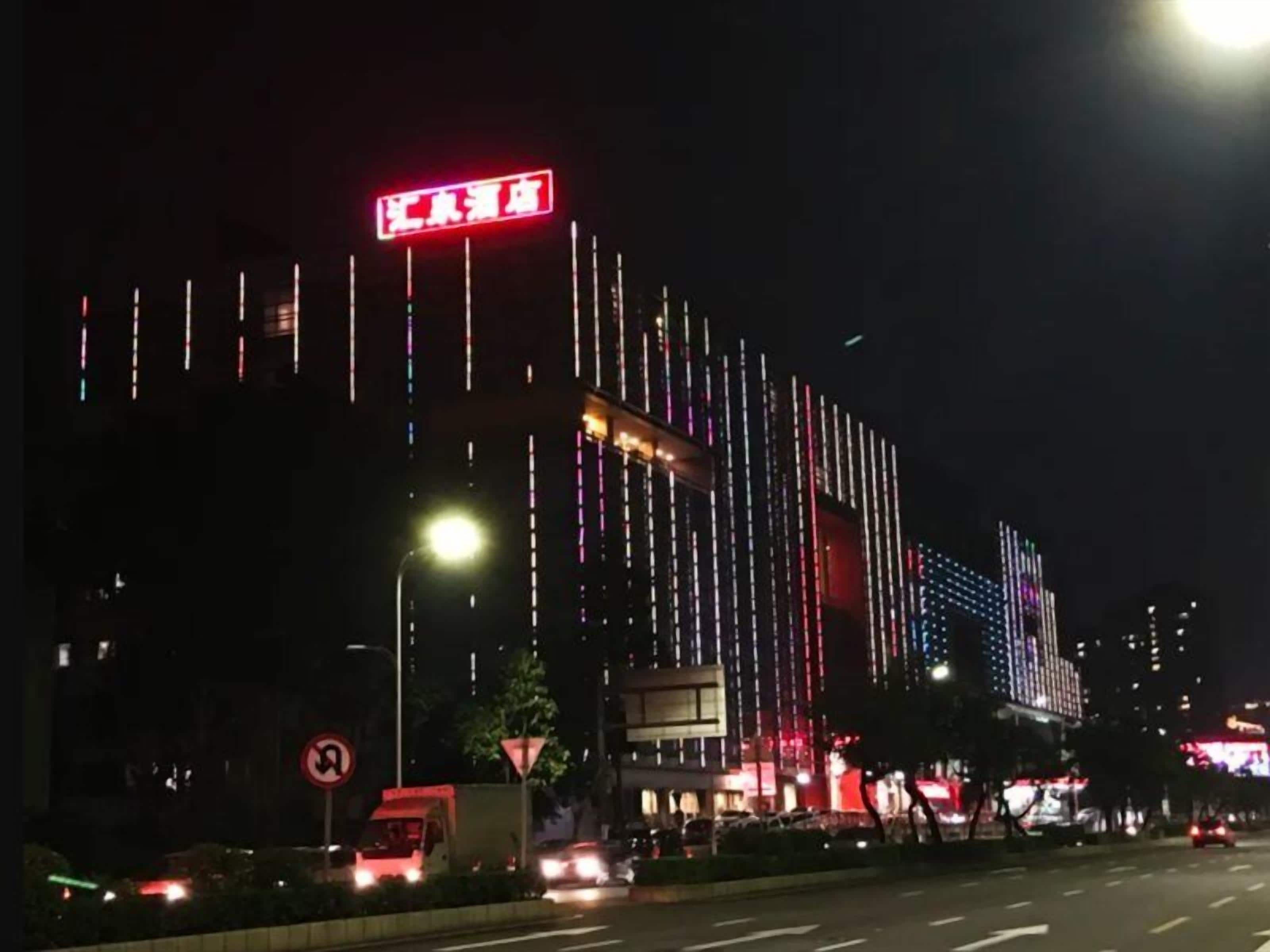 A building with vertical light strips and a prominent red sign.