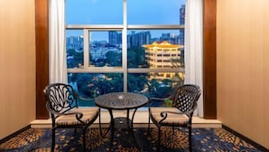 A room with a large window, two chairs, a small table, and a patterned carpet. - Huiquan Hotel (Zhongshan)