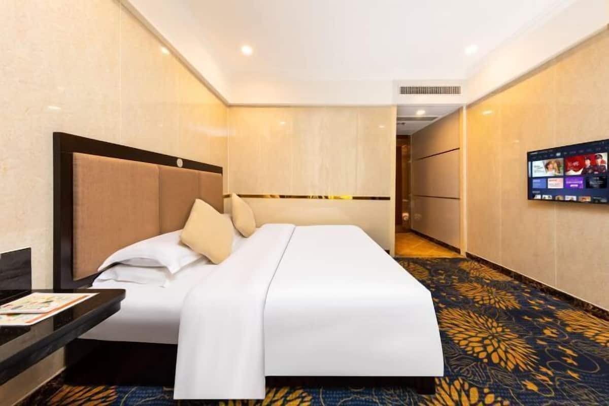 Een hotelkamer met een bed, een televisie aan de muur en een vloerbedekking.