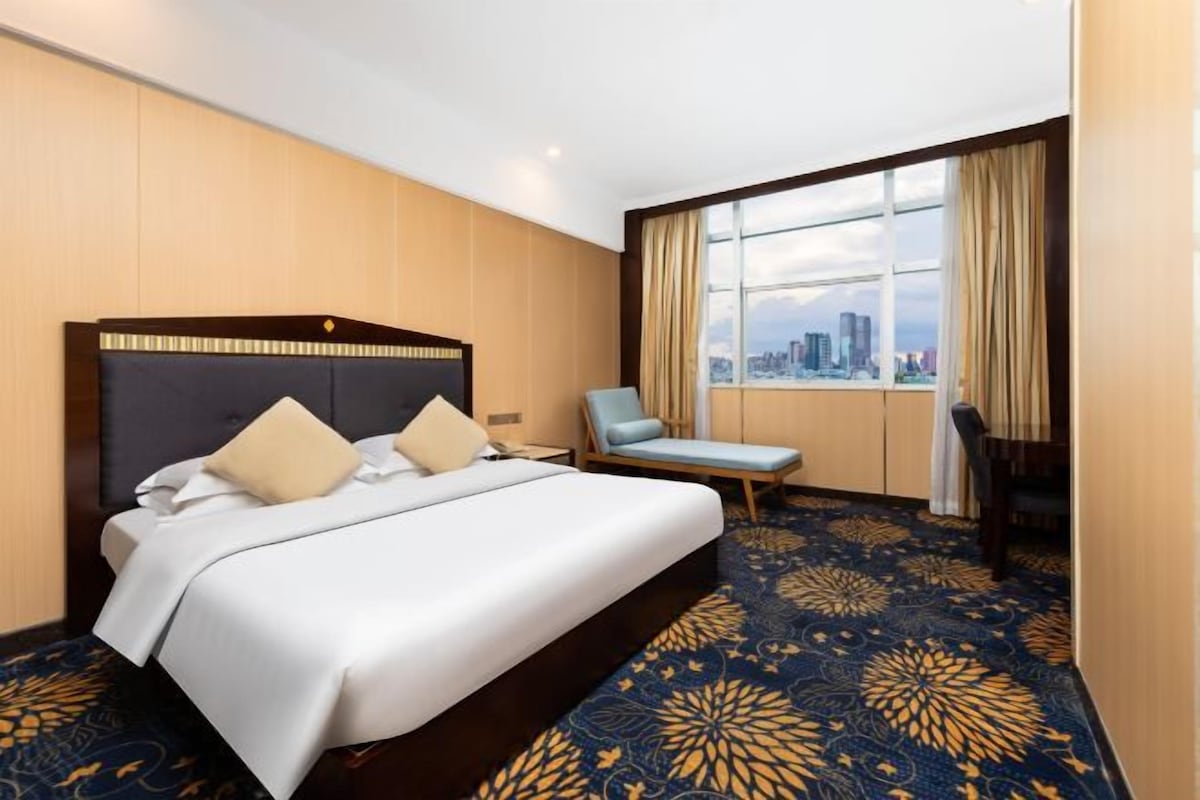 Une chambre d’hôtel avec un grand lit, une chaise, un bureau et une vue sur la ville.