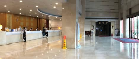 Un hall d’entrée spacieux, doté d’un comptoir de réception, d’une grande colonne et offrant une vue dégagée sur l’entrée.