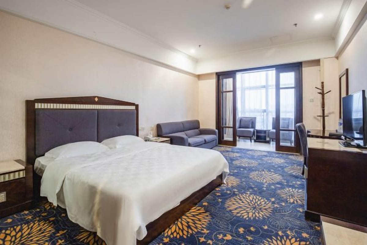 Une chambre d’h ôtel avec un grand lit, un canapé, un bureau et une télévision.