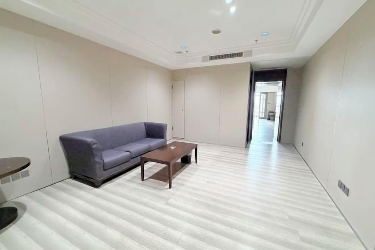 Une pièce spacieuse avec un canapé gris, une table basse en bois et un parquet de couleur claire.