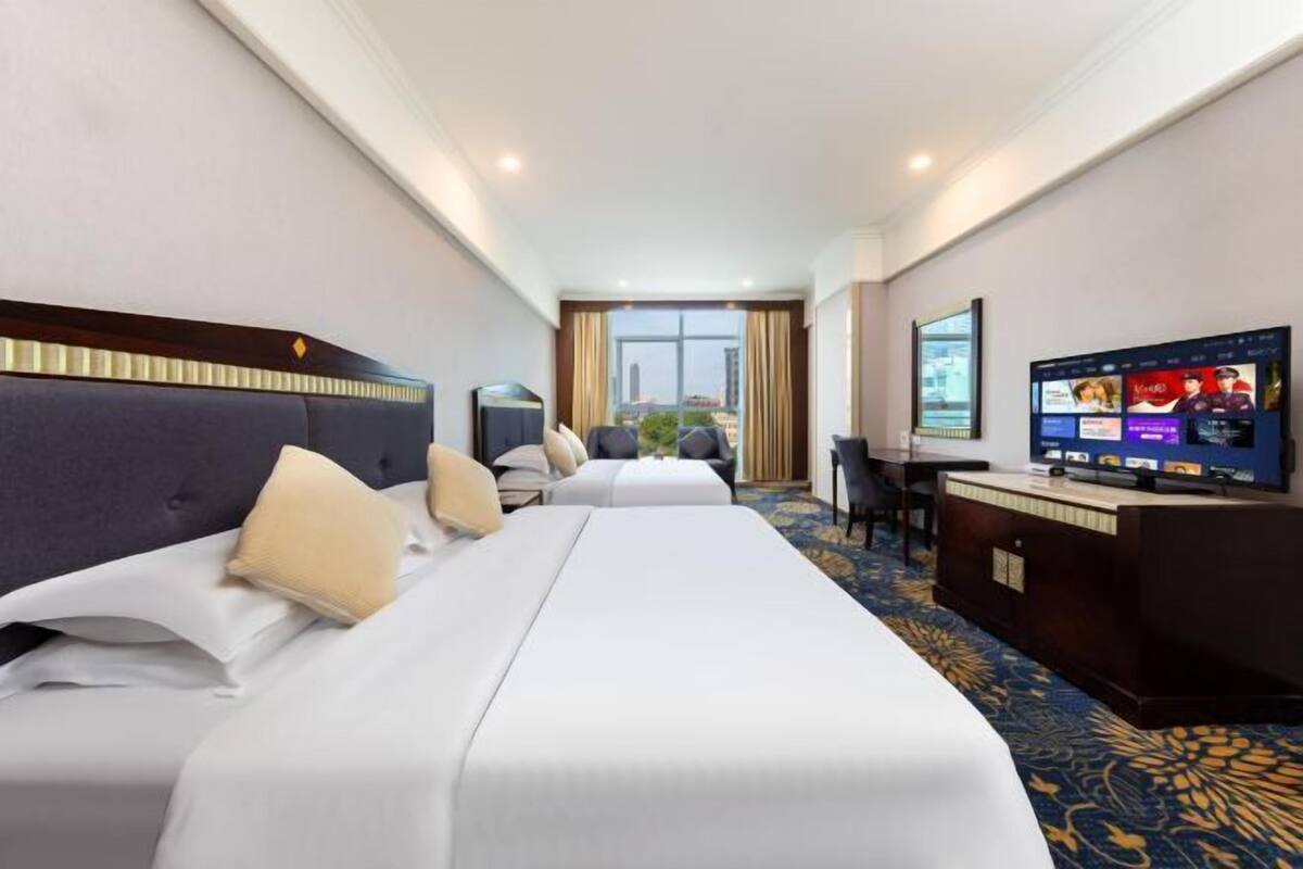 Een hotelkamer met twee bedden, een bureau, een televisie en uitzicht op de stad.