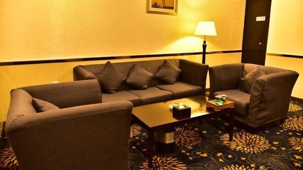 Une chambre d’hôtel comprenant un canapé, une table basse, une lampe et un tapis à motifs.